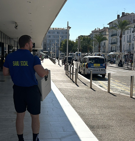 Un bénévole du Samu social tient une caisse en marchant dans une rue.