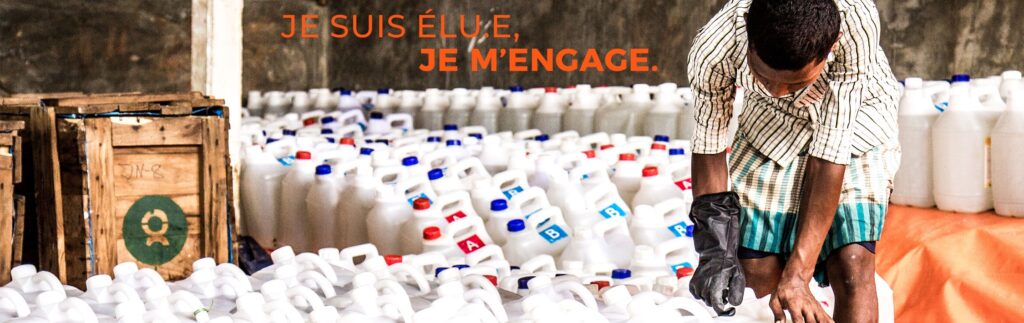 Personne en train de trier de nombreux bidons plastiques blancs dans un espace de stockage, avec le message “Je suis élu.e, je m’engage.” affiché en haut de l’image en lettres orange.